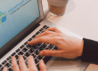 Photo of person tying on laptop computer with CBLP logo on the screen