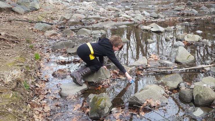 A young girl removing trash from a creek