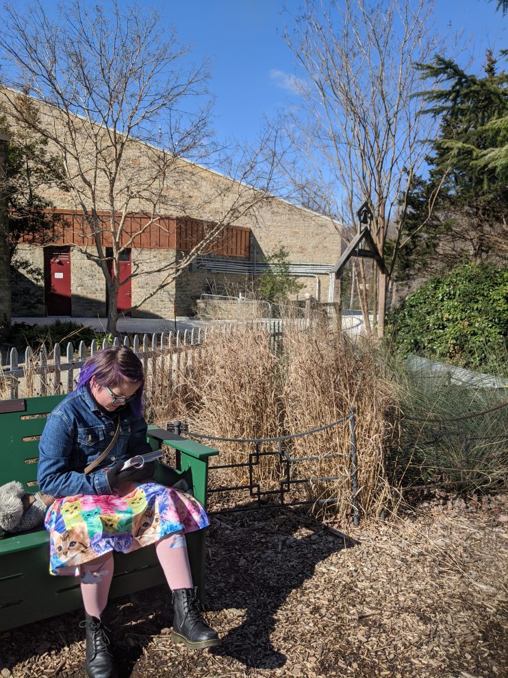 Girl sitting on park bench looking up plants